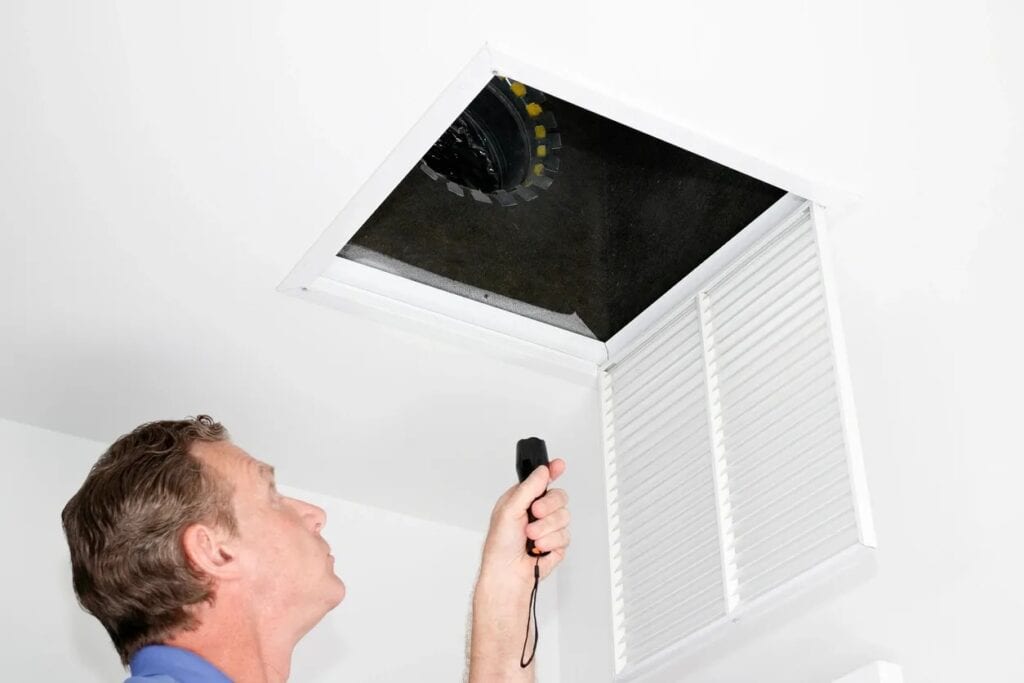 man inspecting HVAC vent